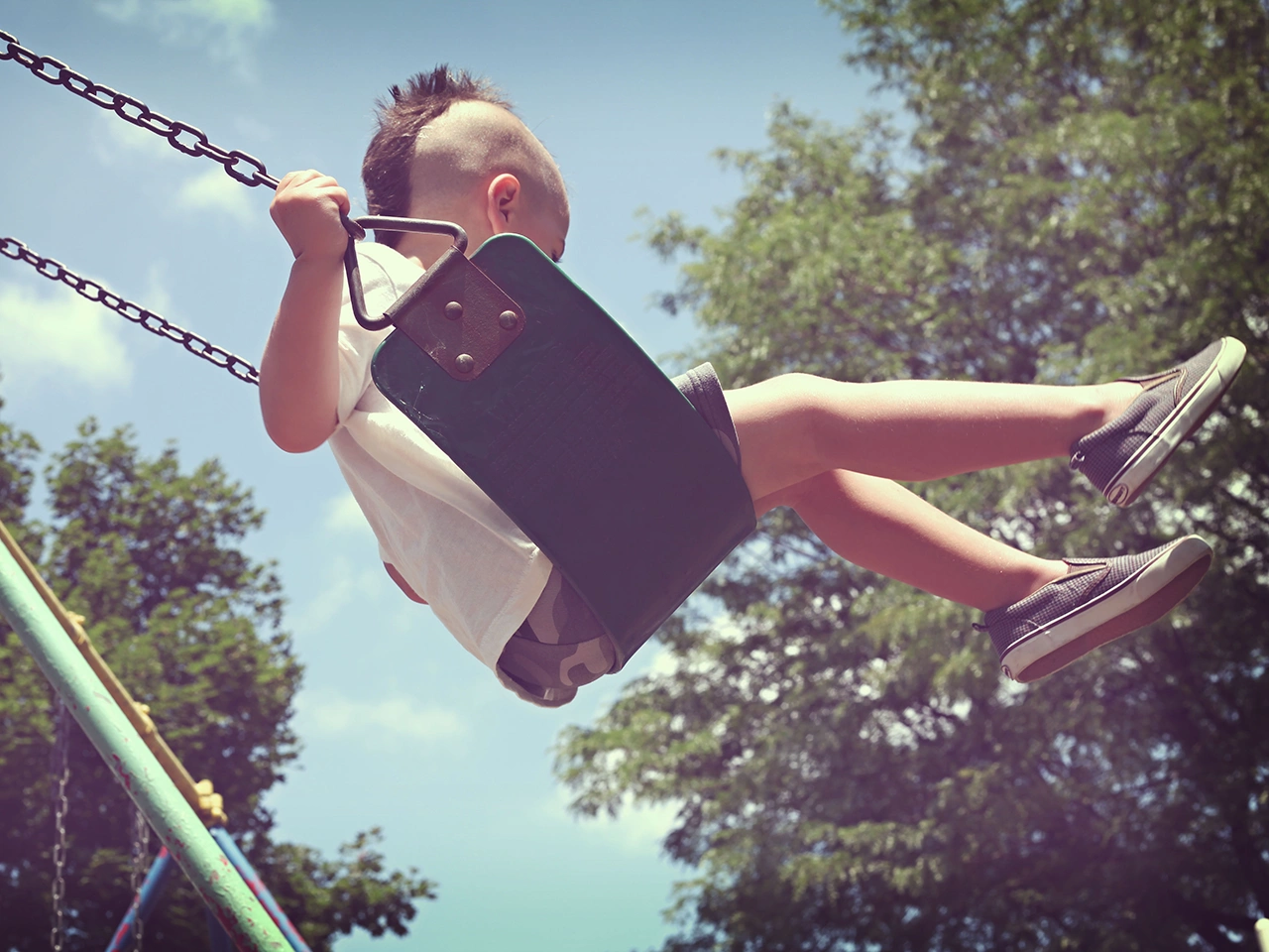 Young boy swinging from a swing